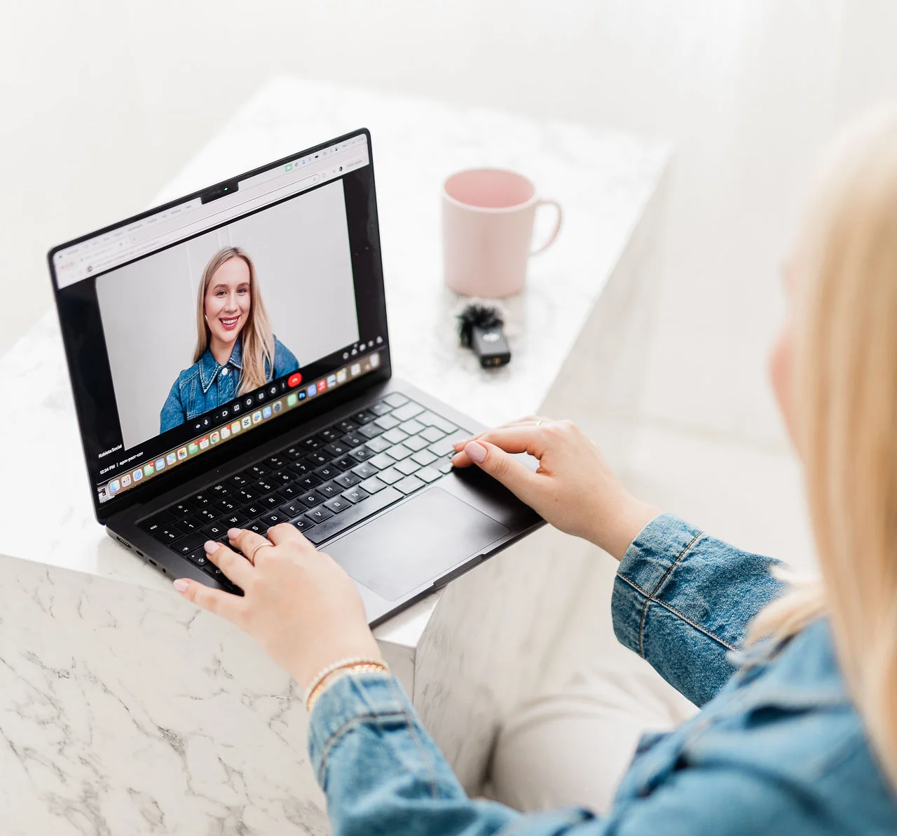 Ujęcie młodej kobiety o blond włosach siedzącej przy biurku i patrzącej na ekran, na którym pokazuje się jej odbicie.